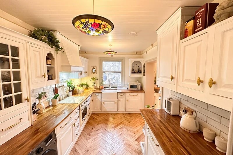 A country style kitchen with fitted units and wooden worktops has a larder, and stairs down to the conservatory.