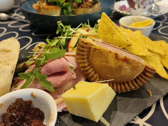 A pork pie platter, with salad, cheese and pickles. and tomato and red onion bruschetta