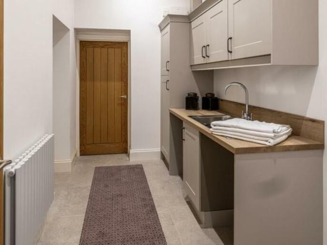 The utility room is fully equipped with fitted base and wall units, including an area designed for a pet grooming shower and plenty of space for everyday laundry needs.