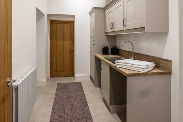 The utility room is fully equipped with fitted base and wall units, including an area designed for a pet grooming shower and plenty of space for everyday laundry needs.