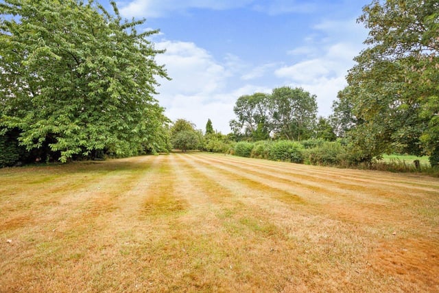 A plot of 1.35 acres includes swathes of lawned garden with a patio area and established trees and shrubs.