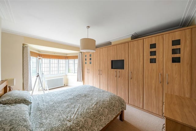The master bedroom has floor to ceiling built in storage units and a canted bay window overlooking the rear garden.