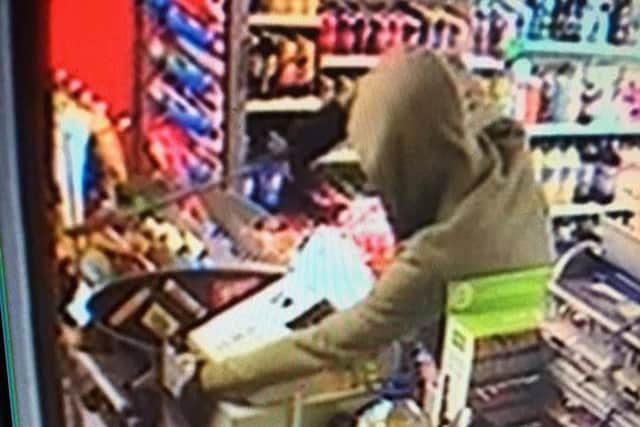 The robber with the 18" blade threatens the shopkeeper.