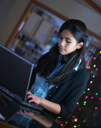 Teen girl working on laptop. Christmas tree in background. Part Scandinavian, Thai descent.