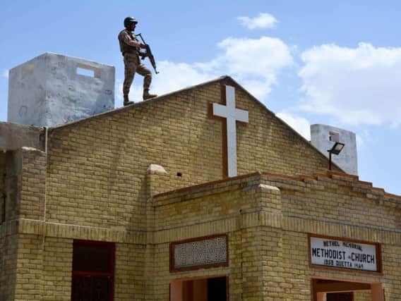 A soldier stands guard on the roof of a Methodist Church.