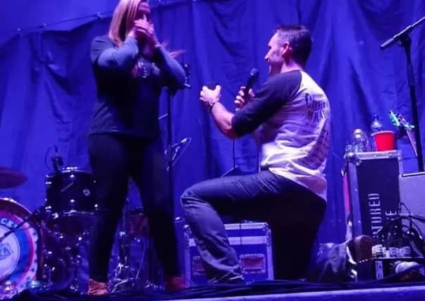 Kriss drops to one knee as he proposes to Clair on stage.