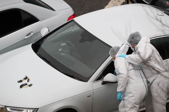 Police forensics officers examine a silver Audi with bullet holes in its windscreen at the scene near junction J24 of the M62 in Huddersfield where a man died in a police shooting during a "pre-planned" operation