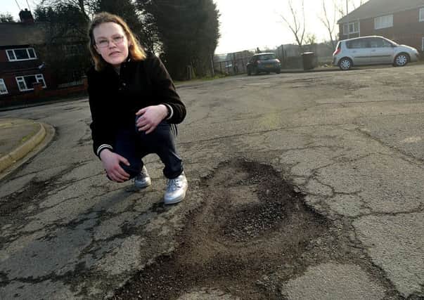 Melanie Morse with one of the potholes on her street.