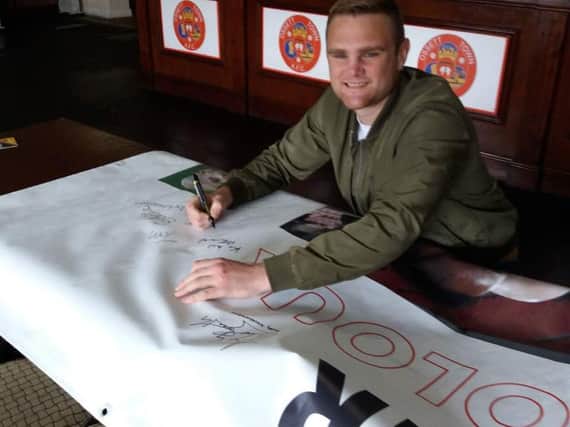 Boxer Andy Townend signing the Cancer Has No Colours banner.