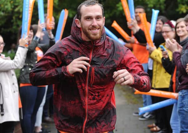 Scott Cranmer is cheered by colleagues as he completes running one million metres in  memory of his late friend Chris Chapman. Picture Scott Merrylees