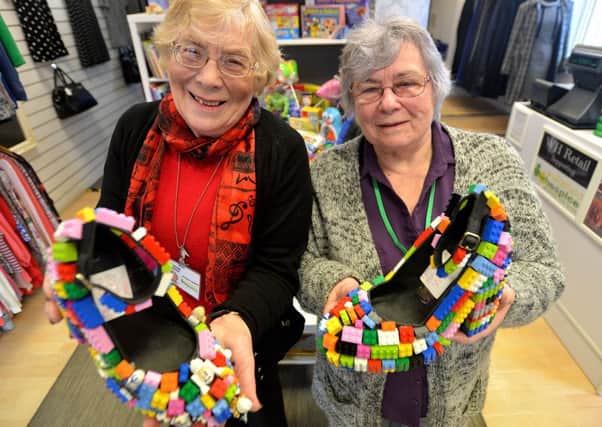 Wakefield Hospice shop on High Street in Horbury has a pair of lego shoes on display to mark the 60th birthday of Lego. The shoes were made by shop manage Tracie Spurr and volunteer Amy Fisher (both NOT on photograph). Picture: Wakefield Hospice shop volunteers Carol Bennett and Pauline Clark with the pair of Lego shoes.